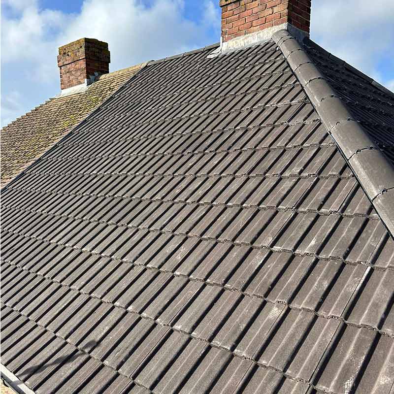 Finished grey flat interlocking concrete tile roof with matching ridge tiles and chimney lead flashing in Portsmouth