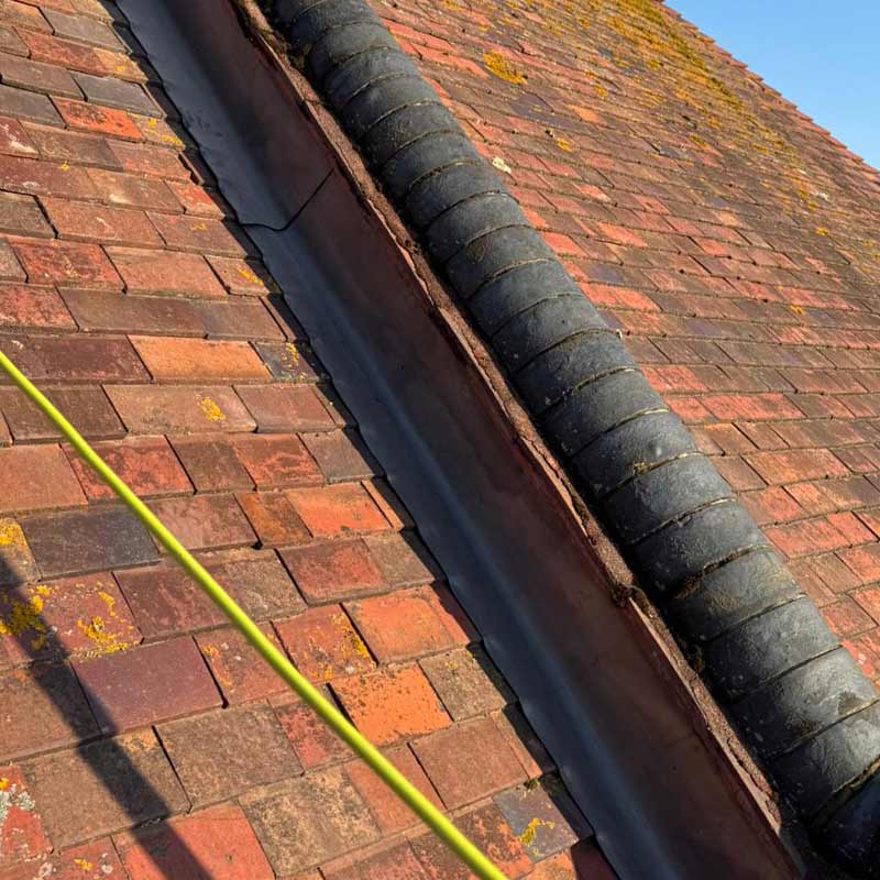 Roof repair beside brick parapet wall with new lead flashing and tile detailing